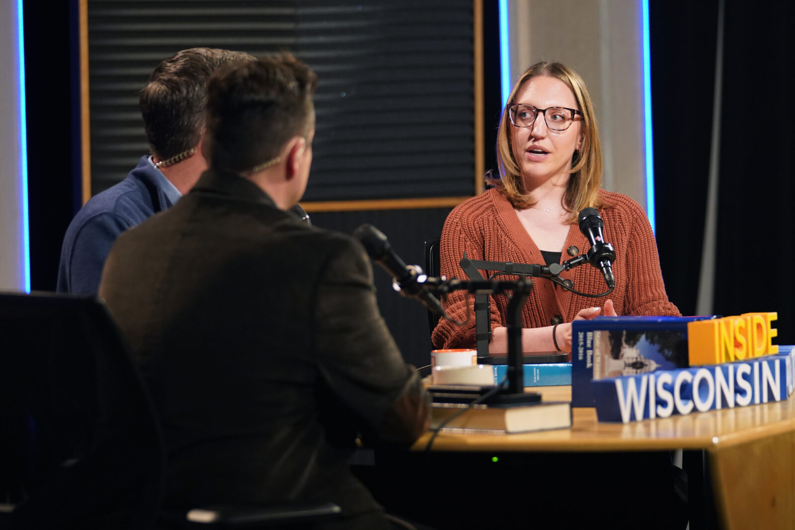 Three hosts sitting around a table, while being recorded for the show Inside Wisconsin Politics.