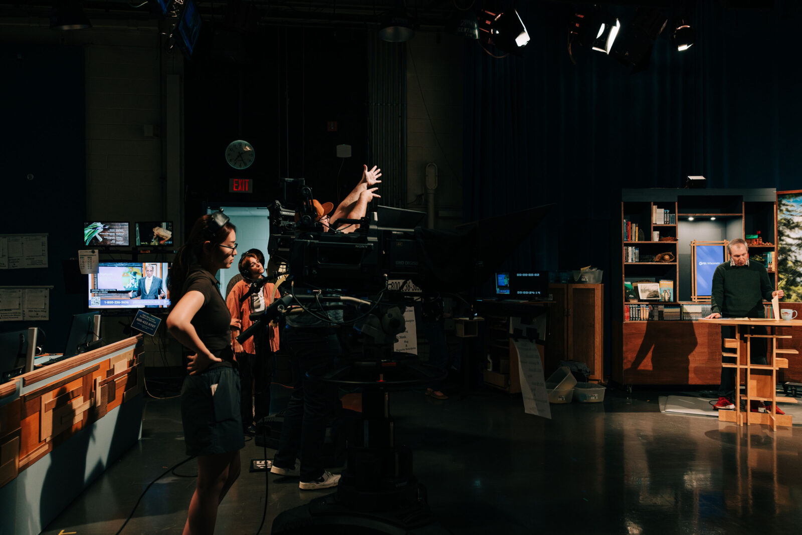 Behind the scenes showing people in a TV studio recording someone on set.